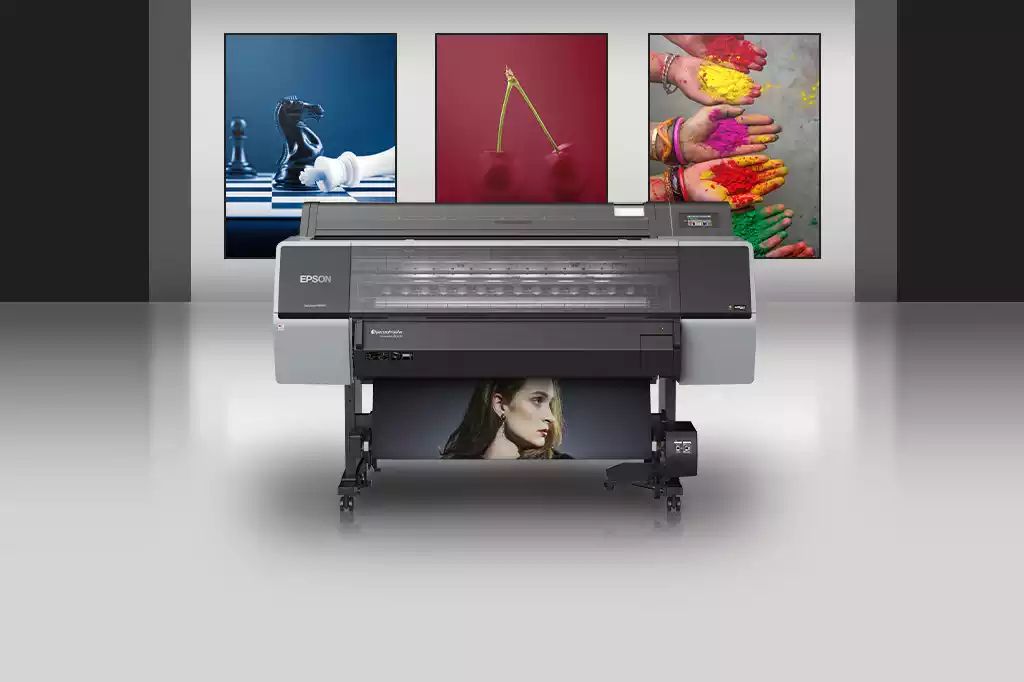 Frontal de impresora de gran formato frente a láminas impresas a todo color. Color de la impresora gris y negro. Soporte con ruedas. Gama SureColor modelo SC-P9500