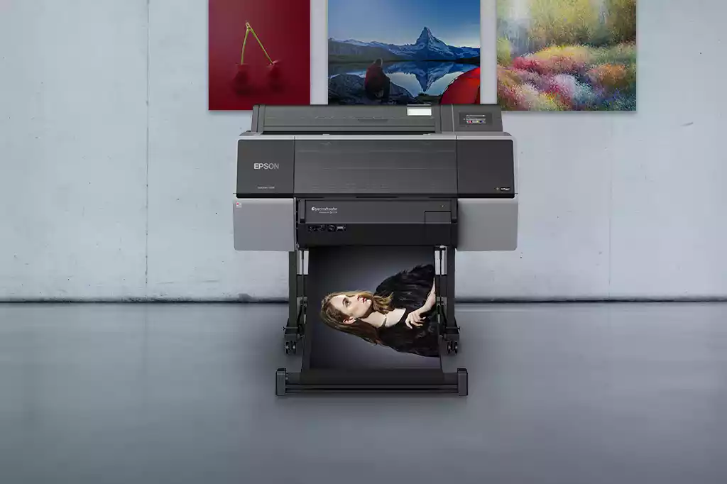 Frontal de impresora de gran formato frente a láminas impresas a todo color. Color de la impresora gris y negro. Soporte con ruedas. Gama SureColor modelo SC-P7500.